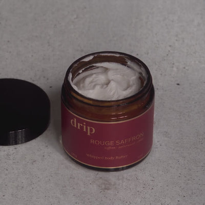 Hands scoop drip Rouge Saffron whipped body butter and swipe it across the palm